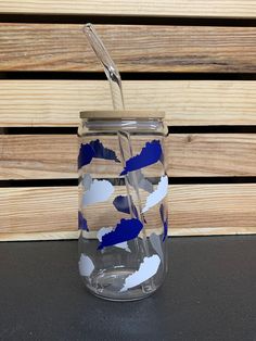 a blue and white glass jar with a straw sticking out of the lid, sitting on a table