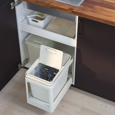 an open cabinet with two bins and a sink in the corner next to it