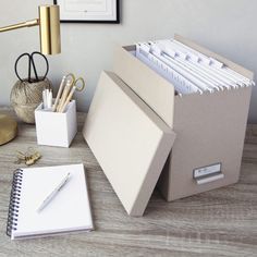 a desk with a binder, pen holder and other office supplies on top of it