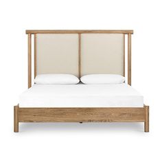 a bed with two pillows on top of it and a wooden frame around the headboard