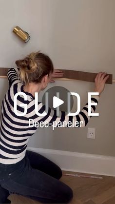 a woman is sitting on the floor with her arms up and head down while holding a wooden plank above her head