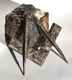 a pair of scissors sitting on top of a piece of metal with intricate designs and filigrees