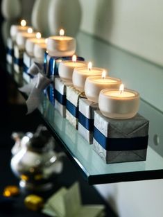 candles are lined up on a glass shelf