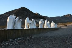 there are many white statues on the side of the road in front of some mountains