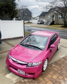 a pink car is parked on the sidewalk