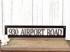 a metal sign that says,'39 airport road'with flowers on the table