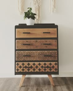 a wooden dresser sitting on top of a hard wood floor next to a potted plant