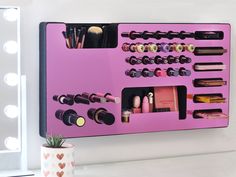 a pink makeup organizer on a wall next to a potted plant