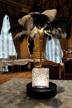 a table topped with a vase filled with feathers and a musical instrument on top of it