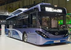 a blue and white bus is on display in a building with people looking at it