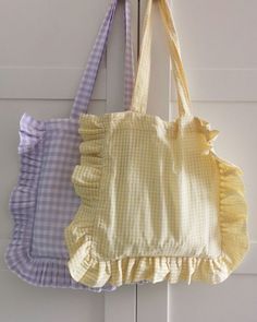 three purses hanging on the wall in front of a white door with blue and yellow gingham