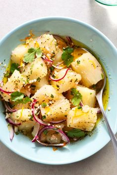 a blue bowl filled with potatoes and radishes on top of a white table