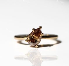 a yellow gold ring with a brown diamond on it's side and reflection in the middle