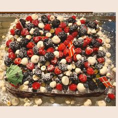 a cake covered in berries, nuts and other toppings on top of a table