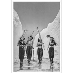 three women in bathing suits carrying skis on their heads and walking through the snow