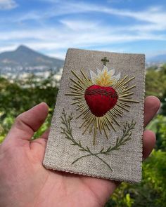 a hand holding up a small piece of fabric with a heart and sun on it