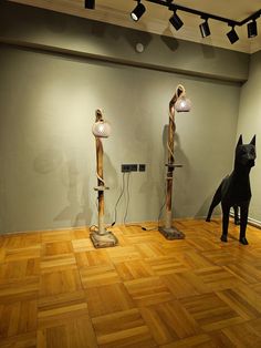 three lamps are on the floor in an empty room with wood floors and two black dogs