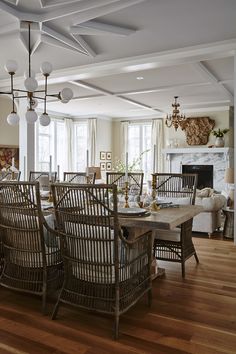 a dining room table and chairs in front of a fire place with a chandelier hanging from the ceiling