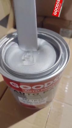 a can of soda sitting on top of a cardboard box with the lid open and a white stick sticking out of it