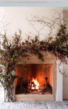 the fireplace is decorated with branches and flowers on it's mantle, which has a fire