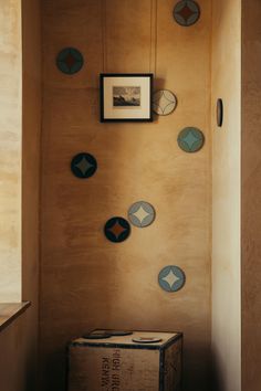 a box sitting on the floor in front of a wall with many plates hanging from it