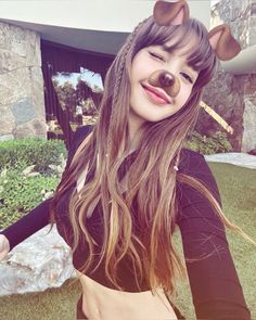 a woman with a fake nose and long hair is posing for a photo in front of a house