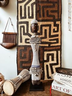 a wooden table topped with a statue next to books and other decorative items on top of it