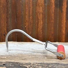 a metal hook with a red handle on a wooden surface