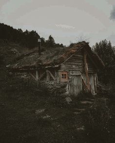 an old wooden cabin with grass roof and stairs leading up to the top of it