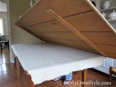 a person standing under a bed with a wooden frame and mattress on it's side