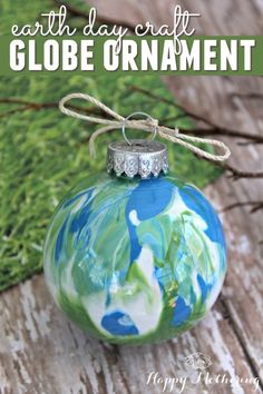 a glass ornament with the words earth day craft globe ornaments on it and green grass in the background