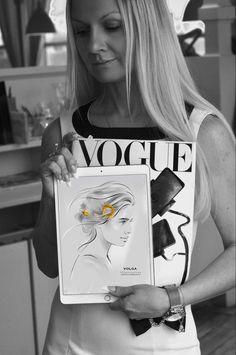 a woman holding up a drawing with a flower in her hair