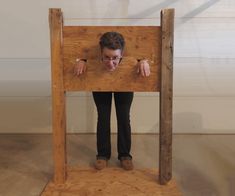 a man is hiding behind a wooden structure