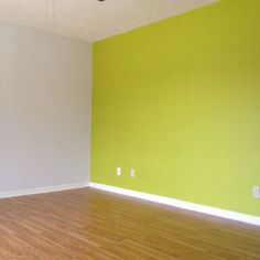 empty room with hard wood flooring and green wall painted in bright yellow, white and gray