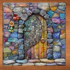 an art piece made out of rocks and stones with a door in the middle that has flowers on it