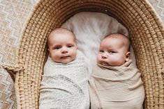 two baby babies laying in a wicker bassinet on top of a blanket