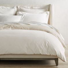 an unmade bed with white sheets and pillows