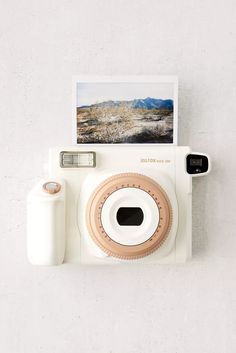 an old polaroid camera sitting on top of a white wall next to a roll of toilet paper