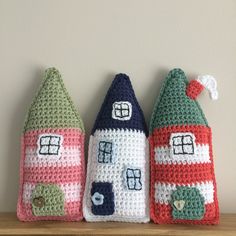 three crocheted houses sitting on top of a wooden shelf