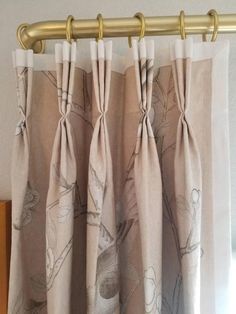 the curtains are hanging in front of a window with flowers on them and gold hardware