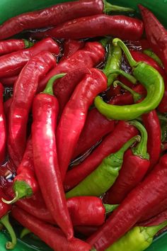 a green bowl filled with red and green peppers