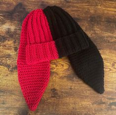 two black and red knitted hats sitting on top of a wooden table