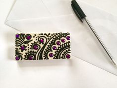 a white envelope with purple and black designs on it, next to a fountain pen