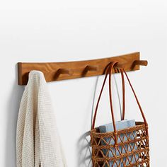 a basket hanging on a wall next to a coat rack with a towel and bag