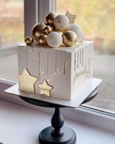 a white cake with gold stars and ornaments on it sitting in front of a window