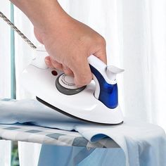 a person ironing clothes on an ironing board with a blue and white handle