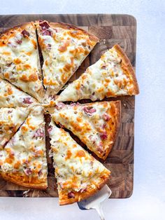 a sliced pizza sitting on top of a wooden cutting board