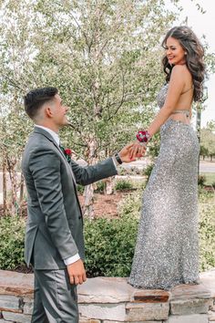 a man in a suit and woman in a dress standing next to each other holding hands