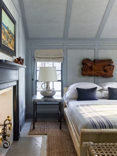 a bed room with a neatly made bed next to a fire place and a painting on the wall