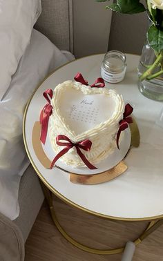 a heart shaped cake sitting on top of a table next to a vase with flowers